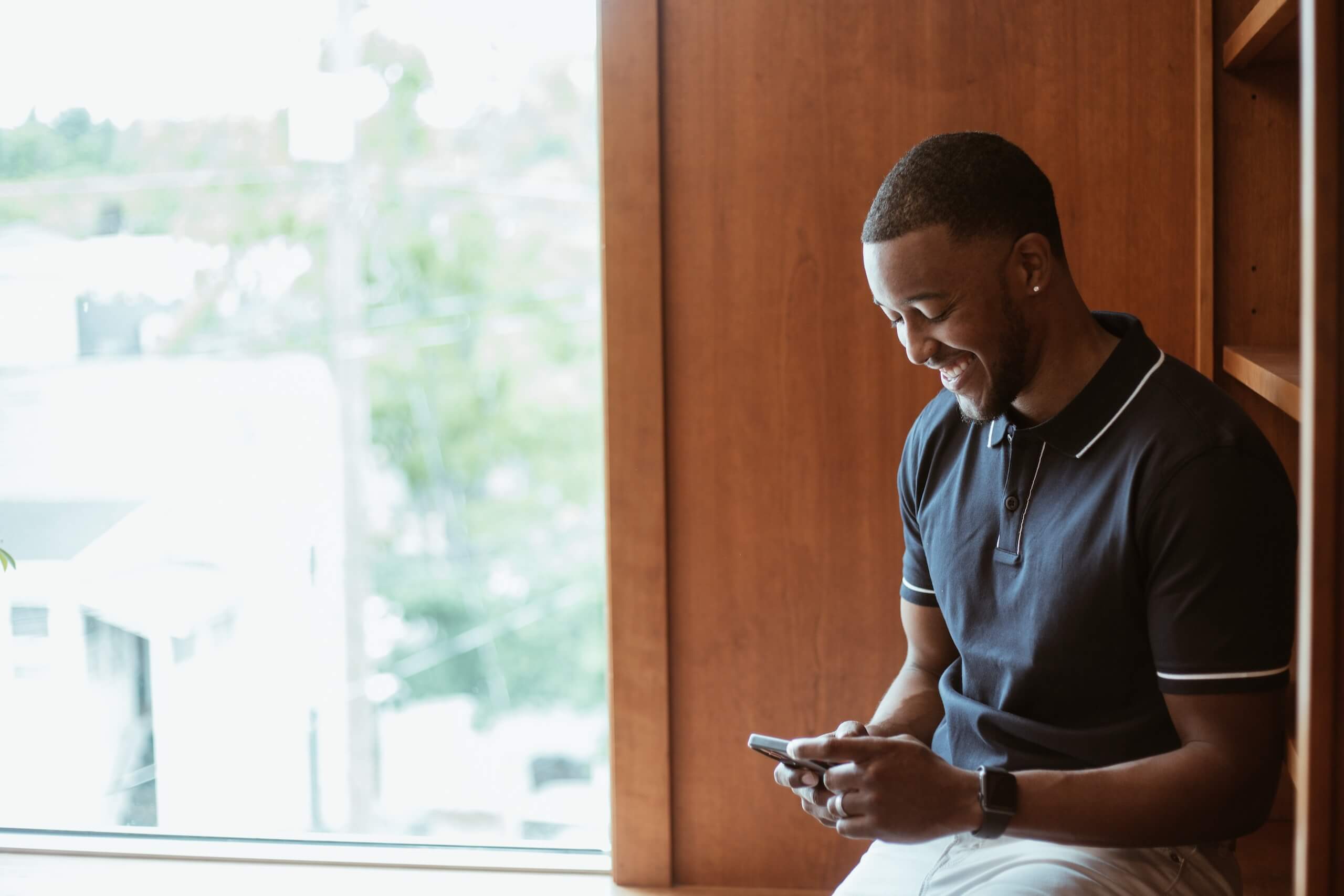 A smiling person looking down and using a phone.
